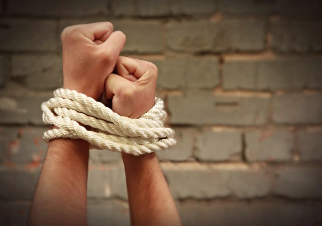 A mans hands tied together with rope.