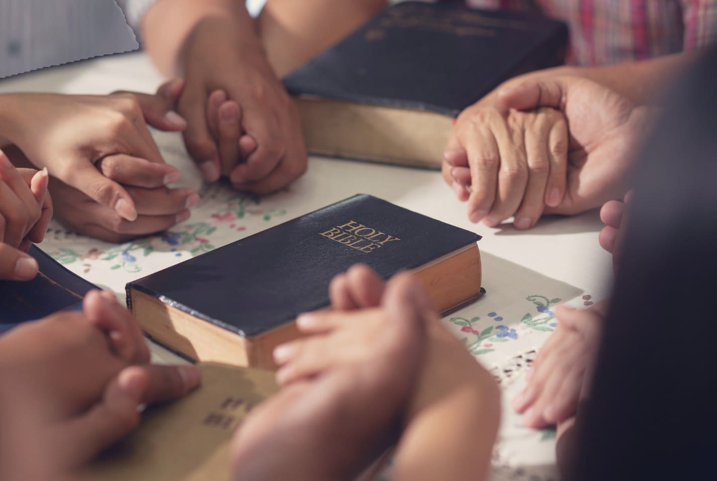 People holding hands around a Bible