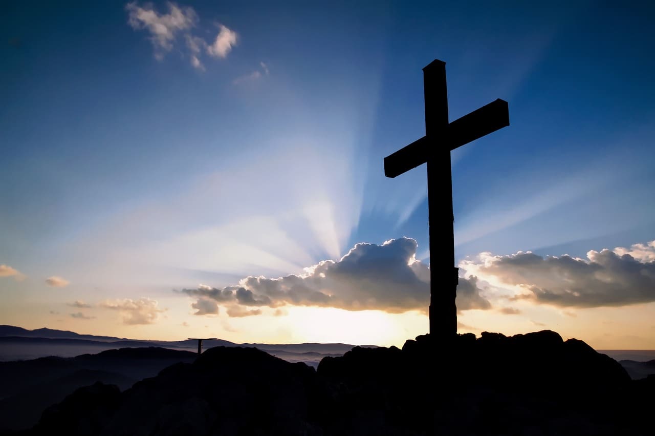 A cross with a sunset in the background