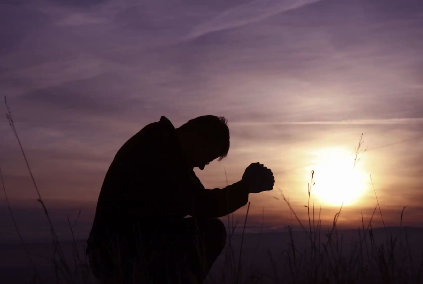 Person praying as the sun is coming up.